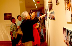 Longtime Chinatown resident and CCED organizer Sophia Wong look at photographs together opening night.